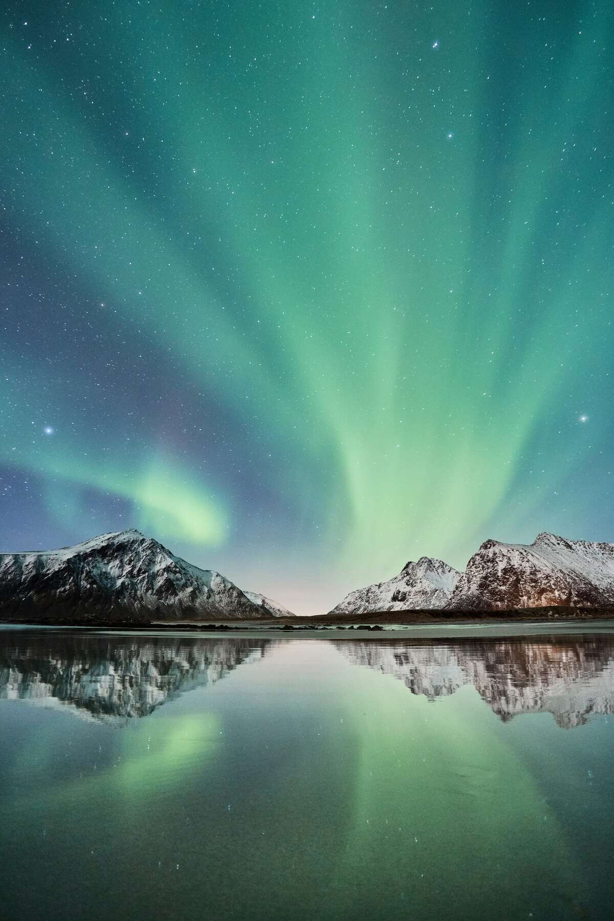 Aurores boréales sur montagnes parsemées de neige en Islande