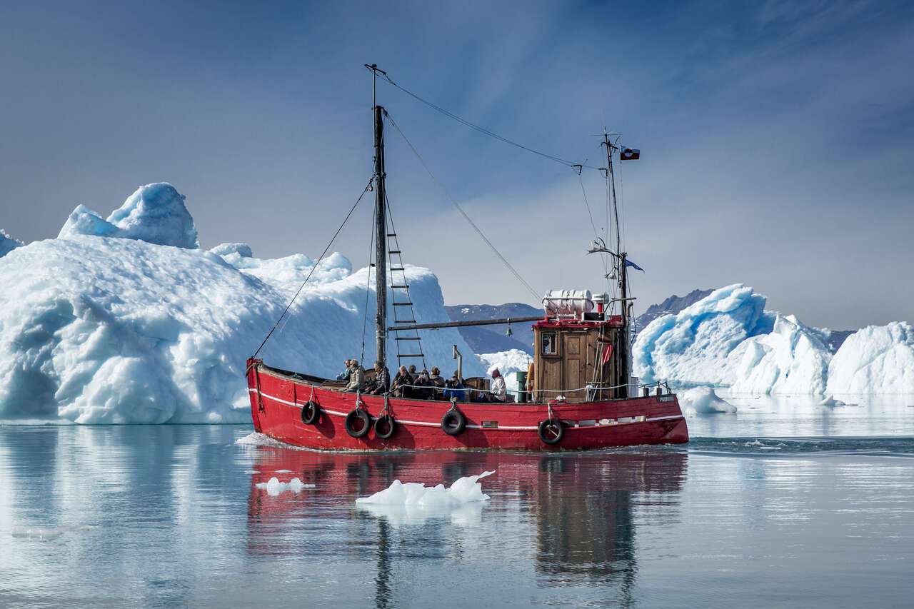 Un bateau proche des immenses icebergs de Qooroq
